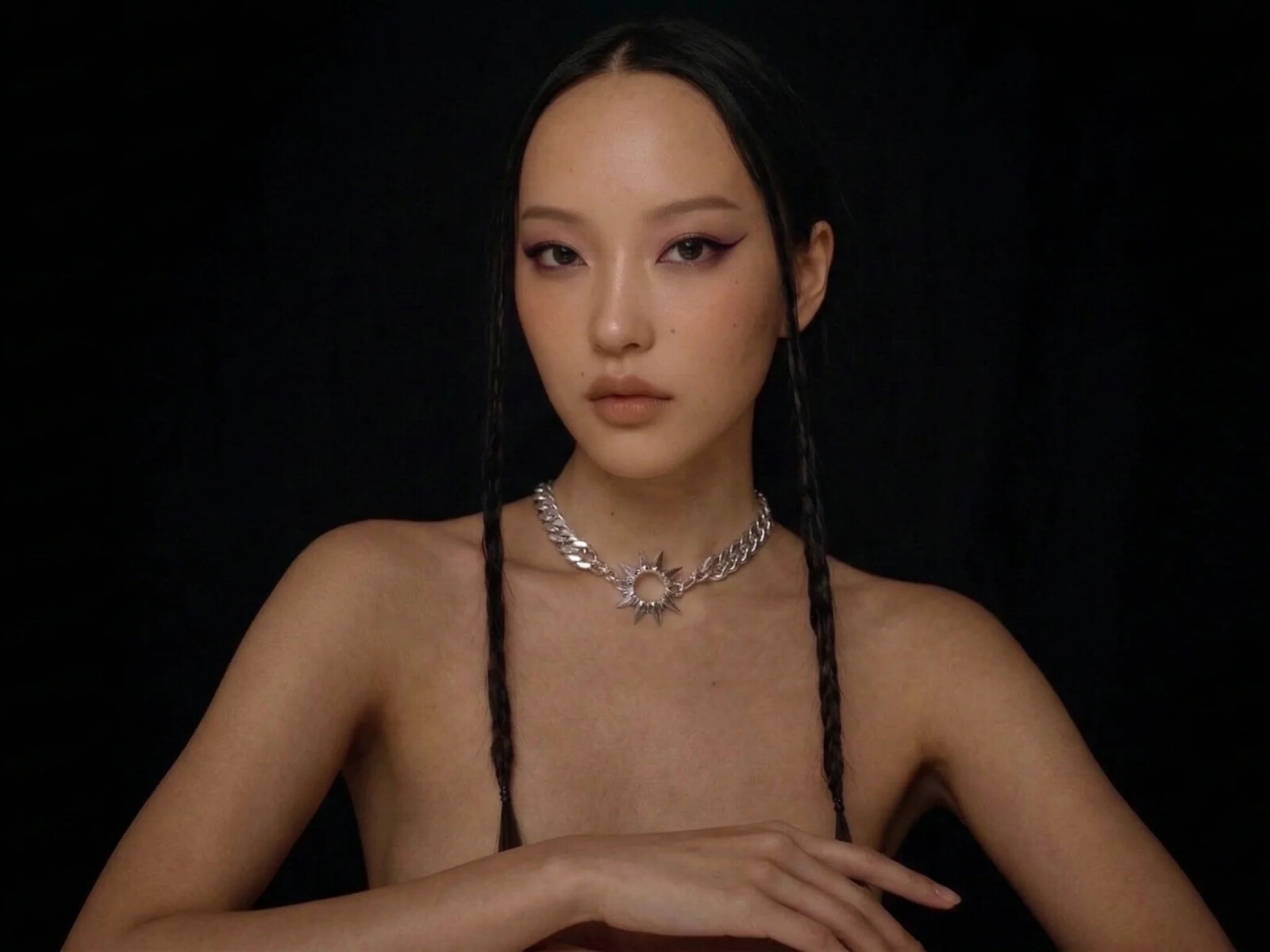 illi Collection brand hero — East Asian model with braided hair and silver sunburst pendant on solid black